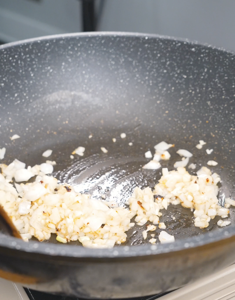 Diced onion and minced garlic softening in a pan for Creamy Garlic Chicken Pasta Recipe.