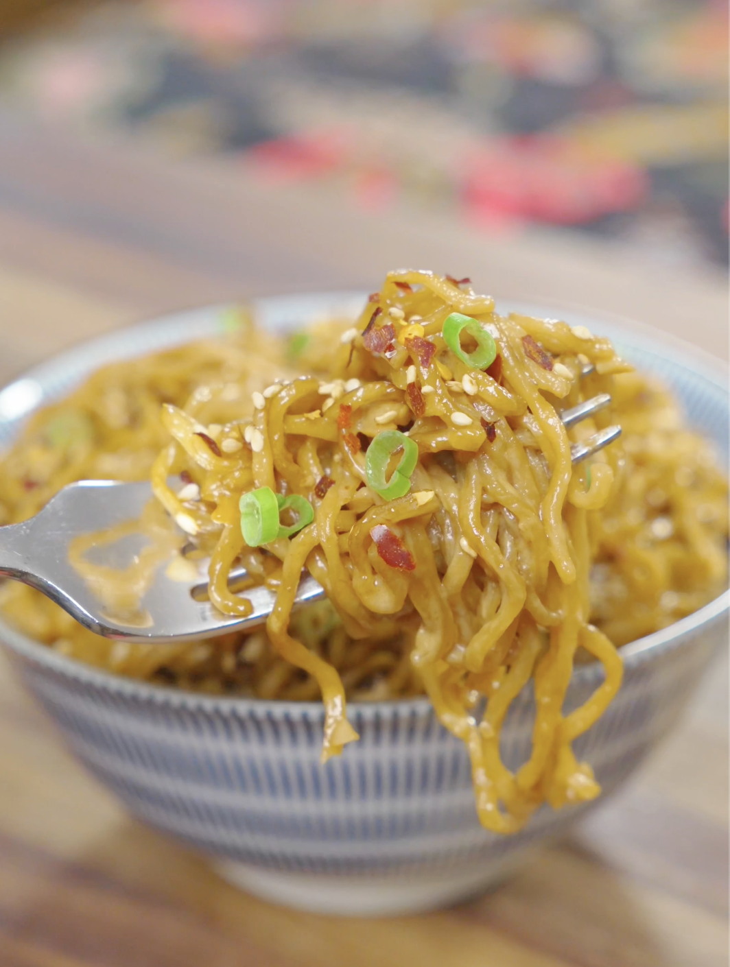 A fork lifting a bite of Creamy Garlic Butter Noodles Recipe coated in a creamy garlic butter sauce with sesame seeds and scallions.