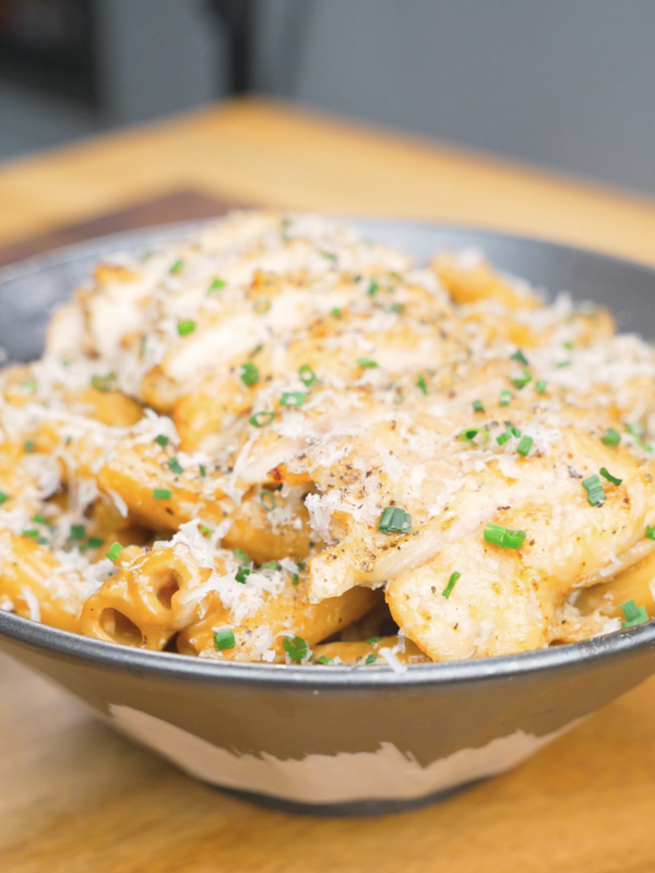 Finished Creamy Garlic Chicken Pasta Recipe topped with sliced chicken, Parmesan, black pepper, and chives.