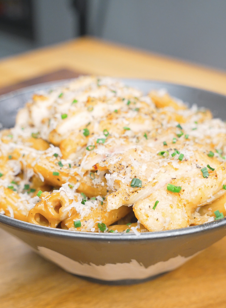 Finished Creamy Garlic Chicken Pasta Recipe topped with sliced chicken, Parmesan, black pepper, and chives.
