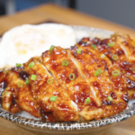 Finished Crispy Sticky Sweet Chicken Recipe sliced over rice with a fried egg and scallions.
