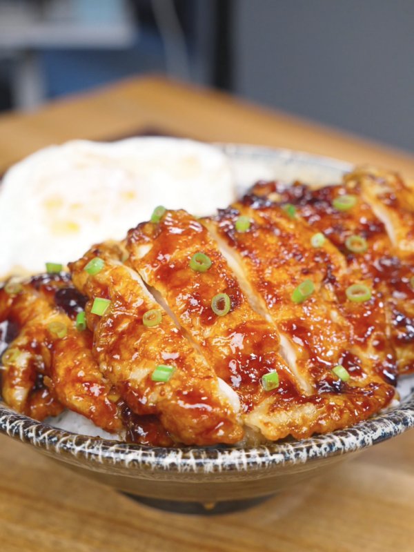 Finished Crispy Sticky Sweet Chicken Recipe sliced over rice with a fried egg and scallions.