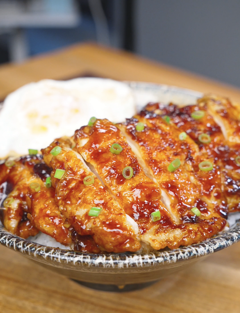 Finished Crispy Sticky Sweet Chicken Recipe sliced over rice with a fried egg and scallions.