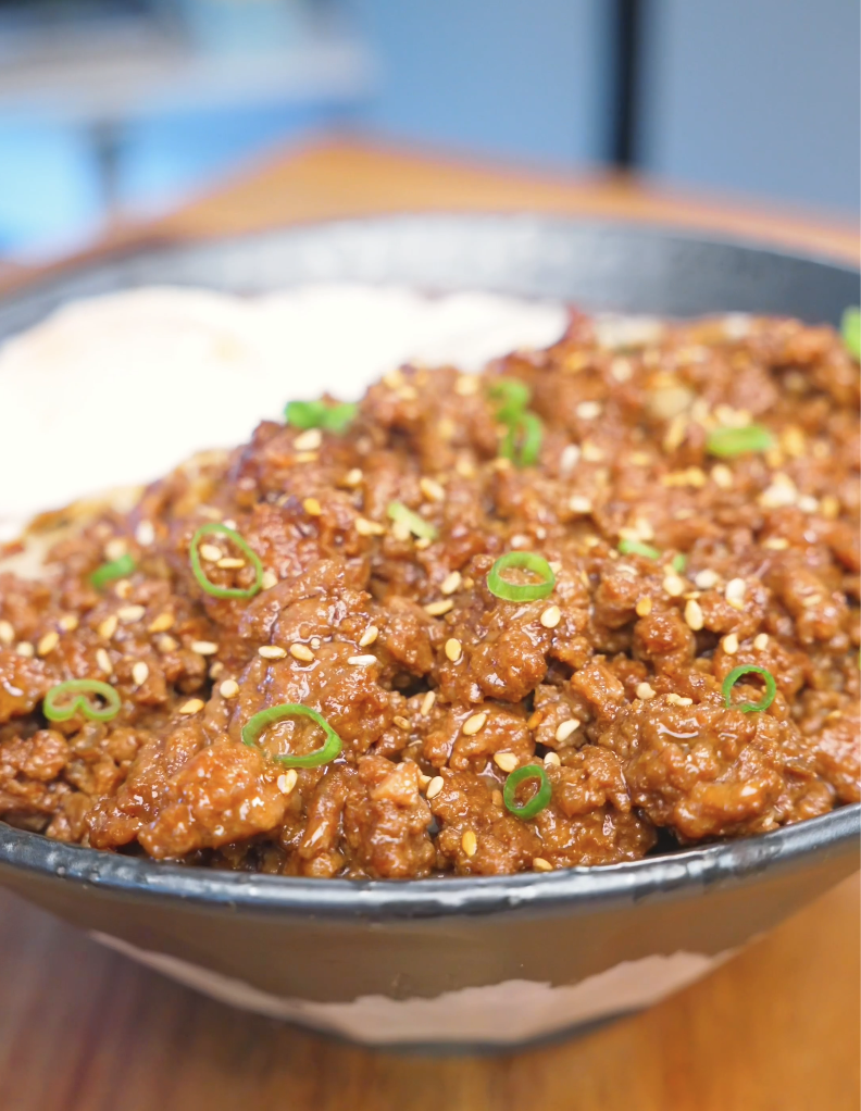 Finished Garlic Ground Beef Recipe over rice topped with sesame seeds, scallions, and a fried egg.