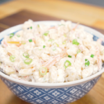 Finished Hawaiian Mac Salad Recipe in a blue bowl with shredded carrots and sliced scallions.