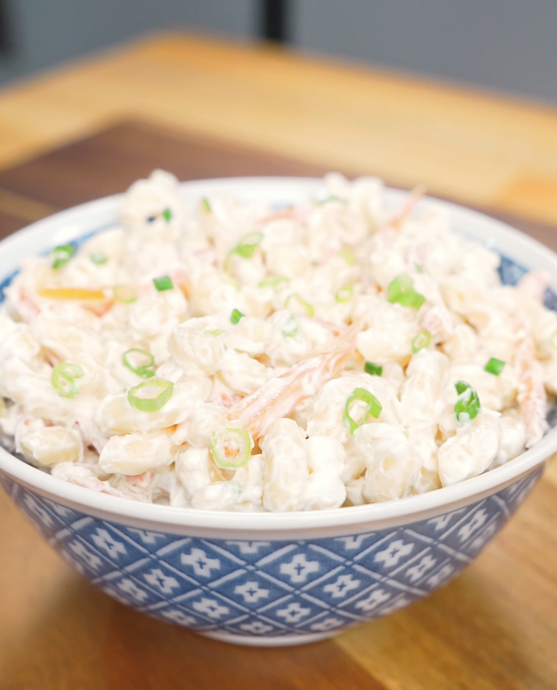 Finished Hawaiian Mac Salad Recipe in a blue bowl with shredded carrots and sliced scallions.