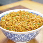 Finished Hoisin Garlic Noodles Recipe in a blue bowl topped with sesame seeds and sliced scallions.