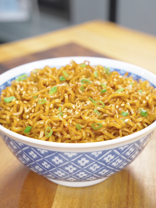 Finished Hoisin Garlic Noodles Recipe in a blue bowl topped with sesame seeds and sliced scallions.