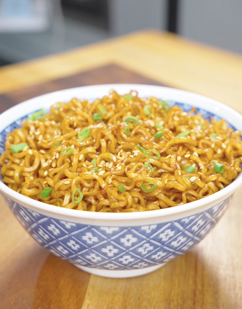 Finished Hoisin Garlic Noodles Recipe in a blue bowl topped with sesame seeds and sliced scallions.