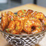 Finished Honey Garlic Shrimp Recipe served over rice in a patterned bowl and topped with scallions.