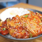 Finished Huli Huli Chicken Recipe sliced over rice with sesame seeds, scallions, and a fried egg.