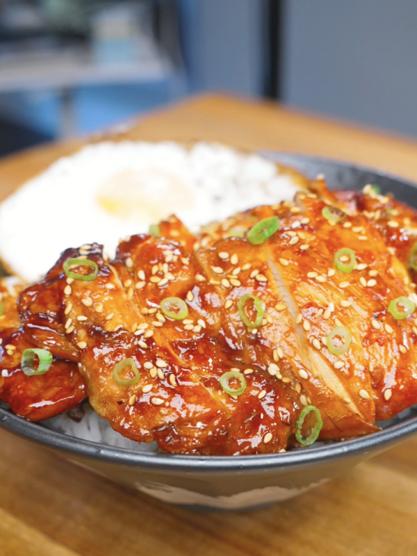 Finished Huli Huli Chicken Recipe sliced over rice with sesame seeds, scallions, and a fried egg.