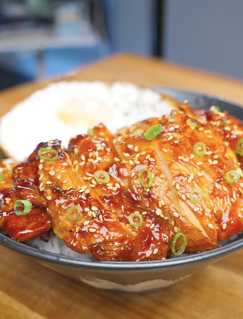 Finished Huli Huli Chicken Recipe sliced over rice with sesame seeds, scallions, and a fried egg.