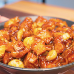 Finished Sticky Garlic Chicken Recipe in a bowl with glazed chicken chunks and whole garlic cloves.