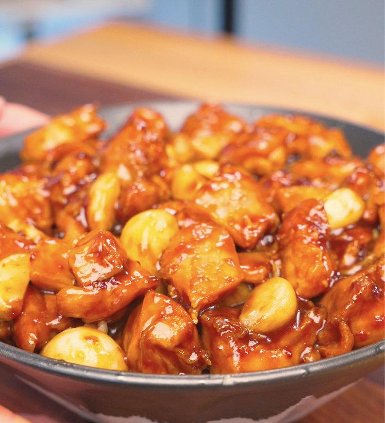 Finished Sticky Garlic Chicken Recipe in a bowl with glazed chicken chunks and whole garlic cloves.