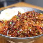 Finished Sticky Sweet Pork Belly Recipe over rice with scallions and a fried egg.