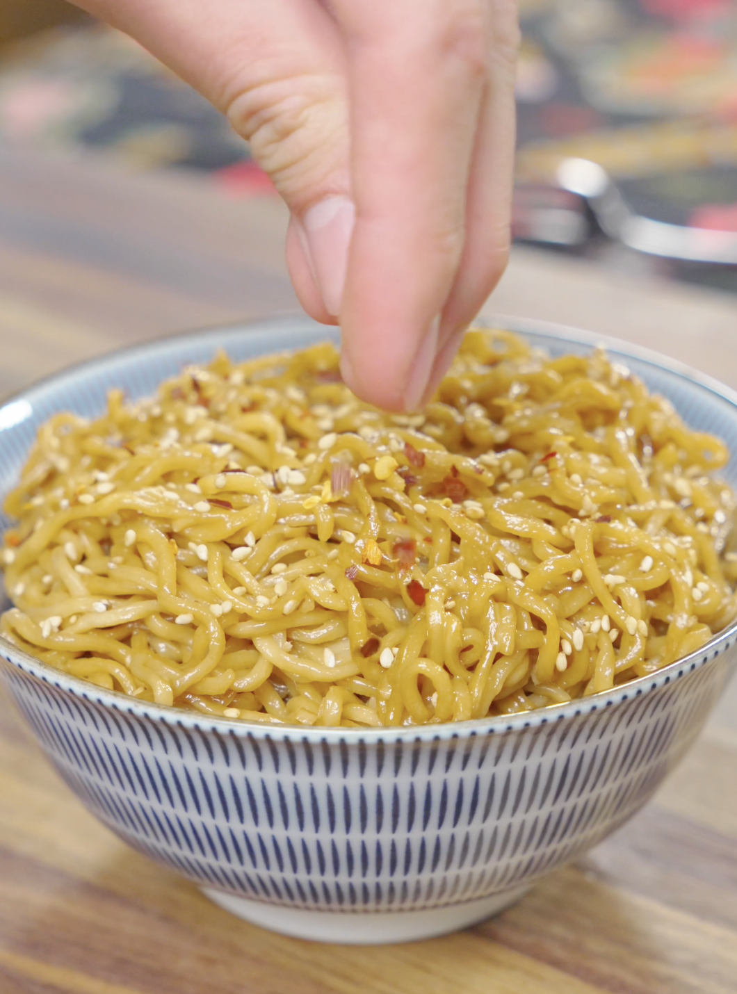 Creamy Garlic Butter Noodles Recipe being finished with sesame seeds, red pepper flakes, and scallions before serving.