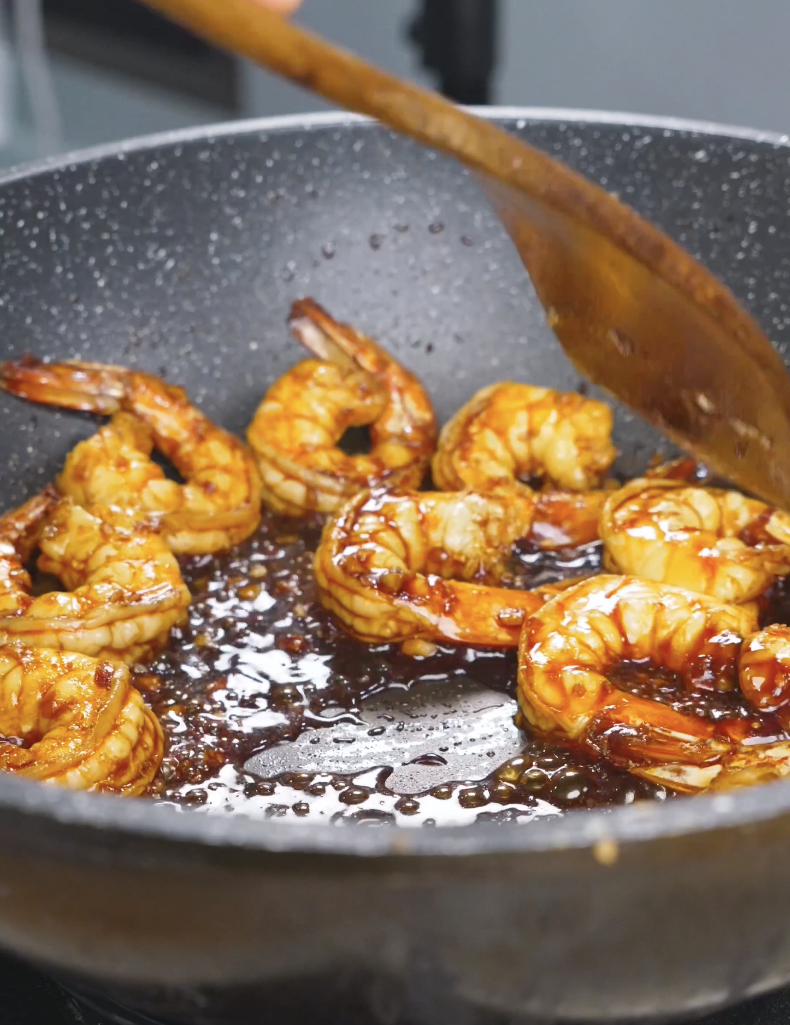 Shrimp cooking in a glossy, reduced honey garlic glaze in the pan for Honey Garlic Shrimp Recipe.
