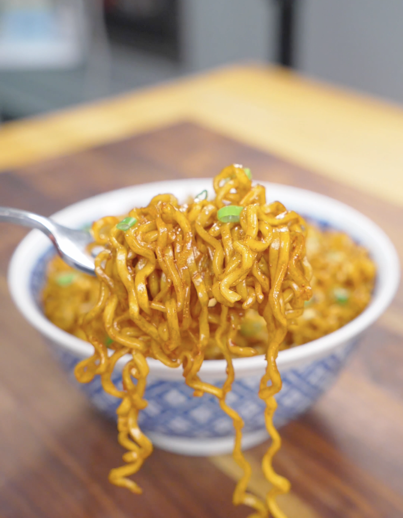A fork lifting a twirl of glossy noodles above the bowl of Hoisin Garlic Noodles Recipe.
