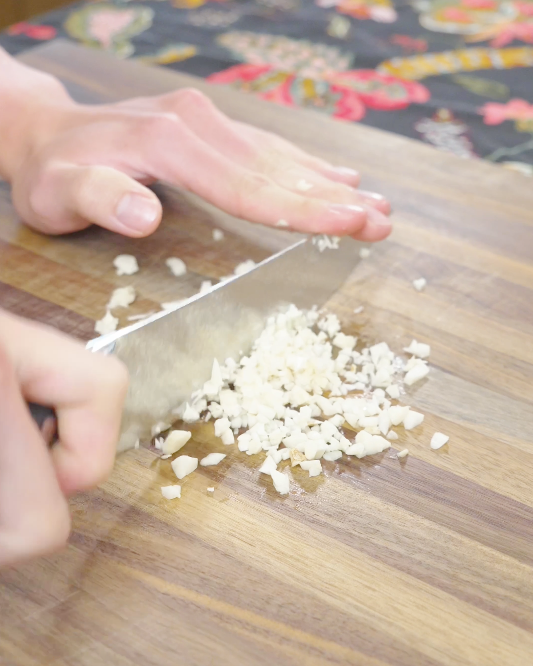 Fresh garlic being finely minced on a cutting board for the Creamy Garlic Butter Noodles Recipe.
