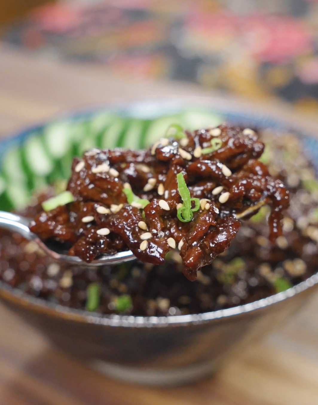 A spoonful of Sticky Sweet Ground Beef Recipe coated in a glossy sweet soy sauce with sesame seeds and scallions.