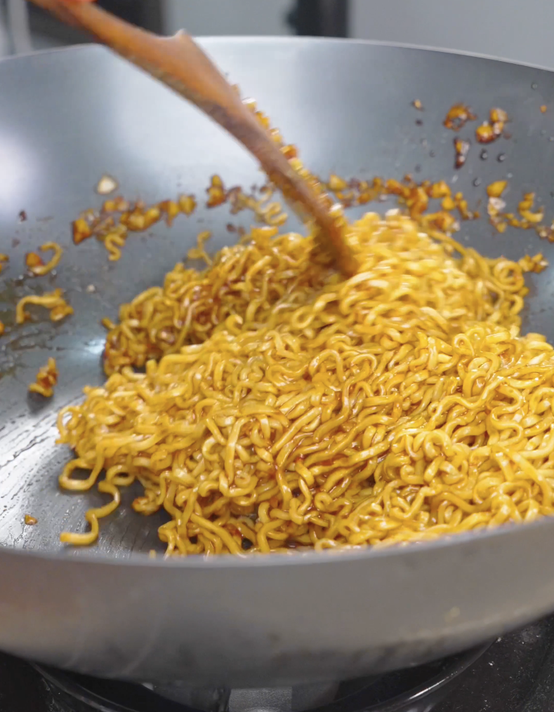 Noodles being tossed until evenly coated in glossy hoisin sauce for Hoisin Garlic Noodles Recipe.