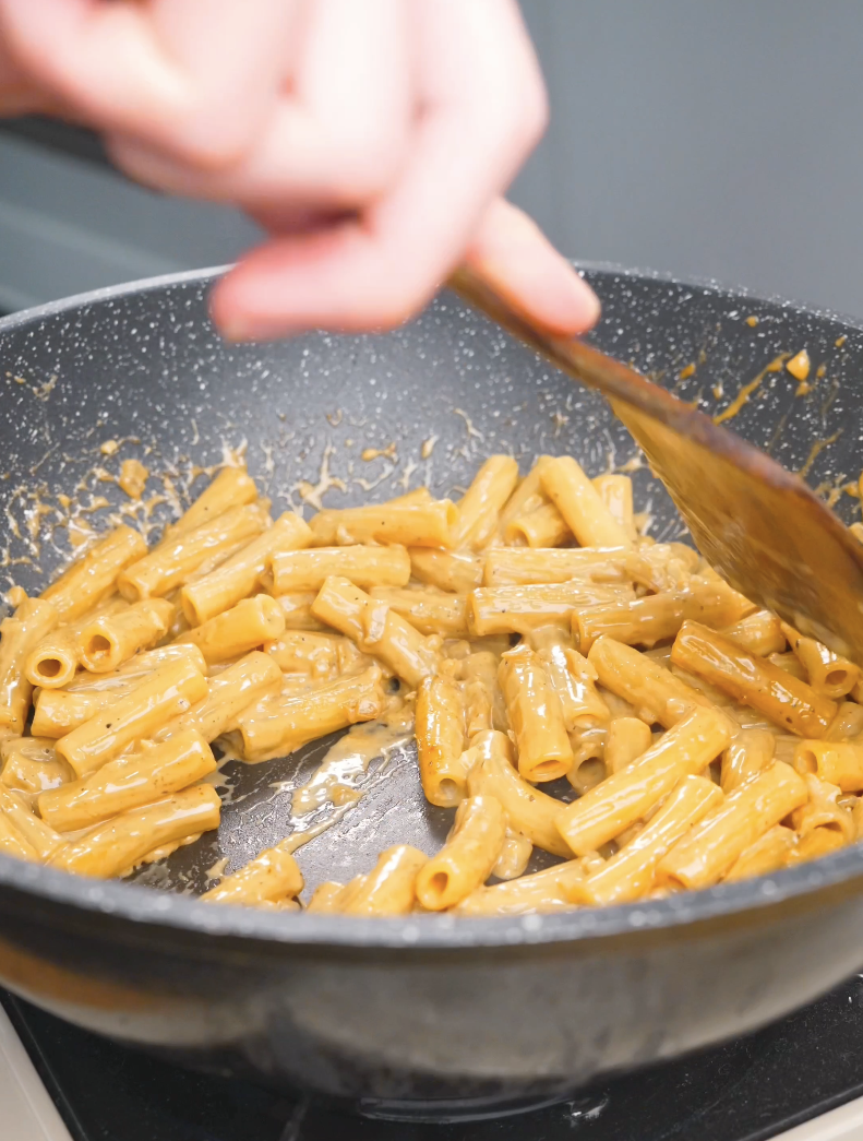 Rigatoni being tossed in the rich garlic cream sauce for Creamy Garlic Chicken Pasta Recipe.