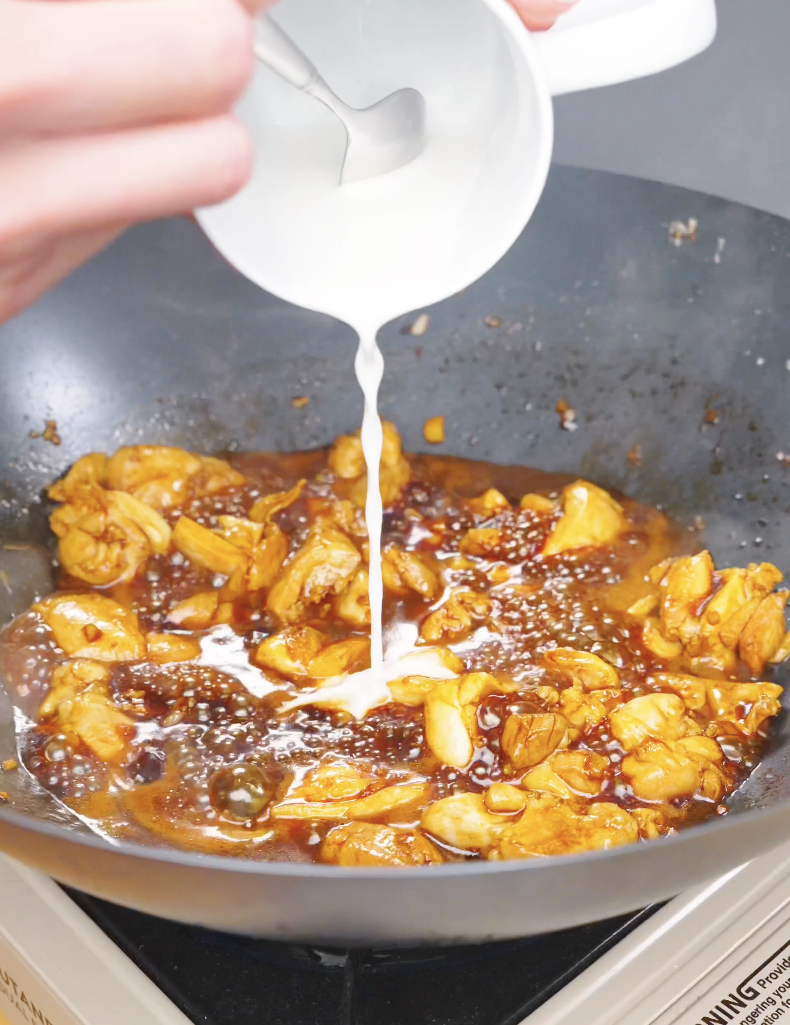 A cornstarch slurry being poured into the sauce to thicken it for Sticky Orange Chicken Recipe.