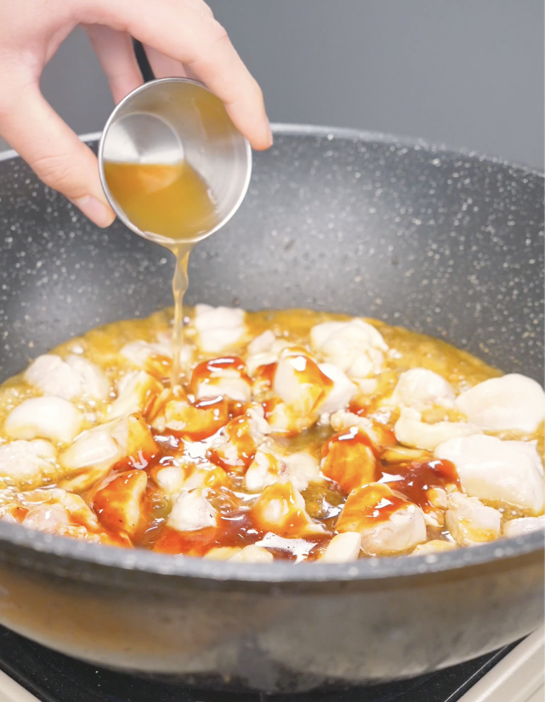 Honey being poured over the chicken and barbecue sauce in the pan for Honey BBQ Chicken Recipe.