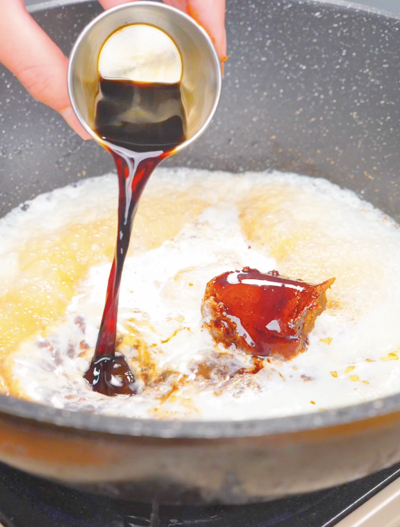 Dark soy sauce being poured over a scoop of miso paste in the creamy base for Creamy Miso Butter Noodles Recipe.