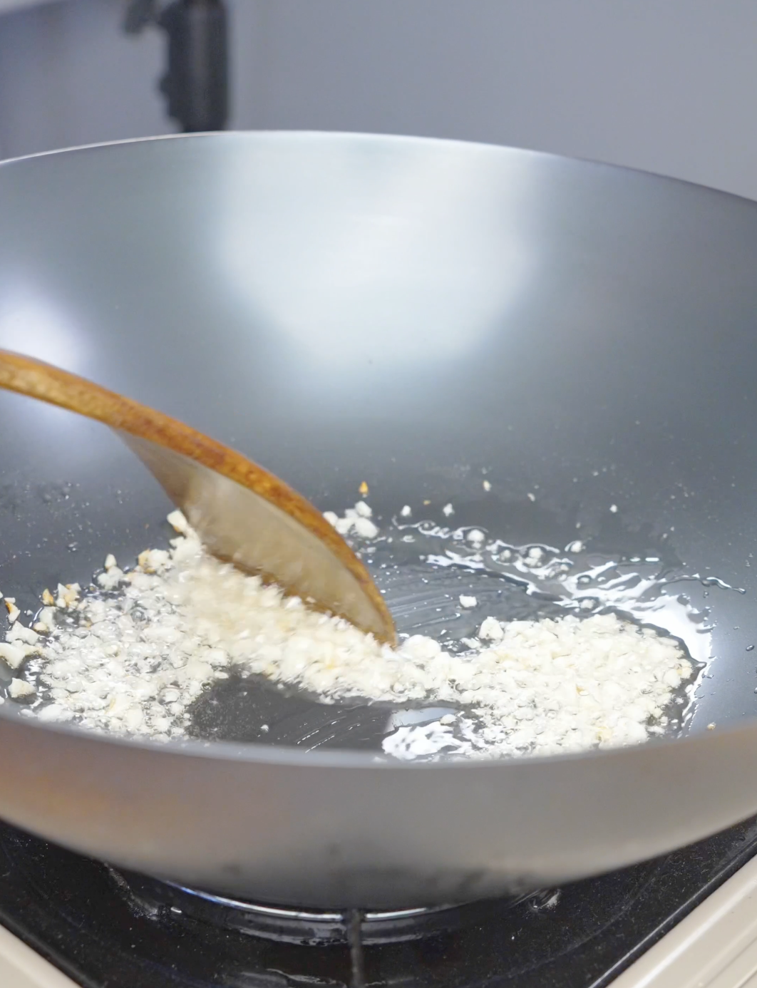 Minced garlic sizzling in oil in a wok while starting Firecracker Chicken Recipe.