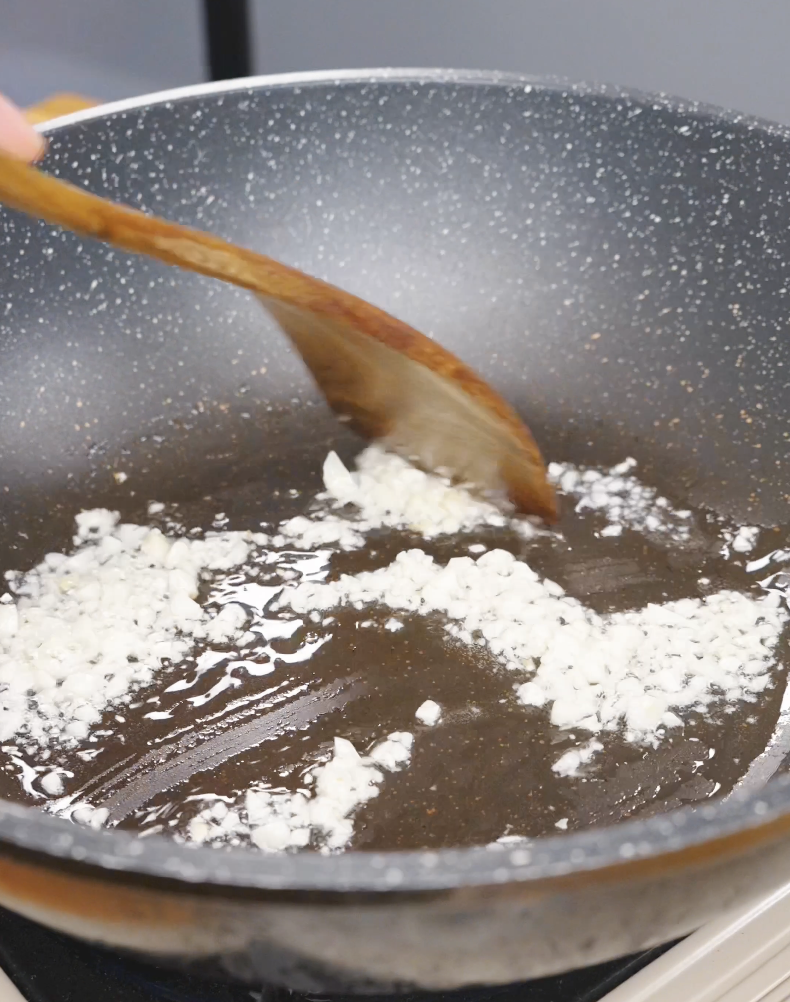 Minced garlic cooking in oil in a pan while starting Sticky Soy Garlic Chicken Recipe.