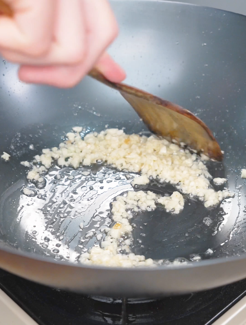 Minced garlic cooking in melted butter in a wok while starting Garlic Butter Ground Beef Recipe.