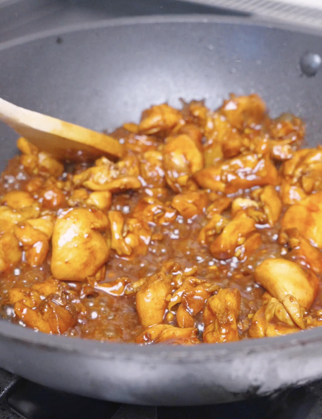 Chicken pieces cooking in a glossy honey sesame sauce in the wok for Honey Sesame Chicken Recipe.