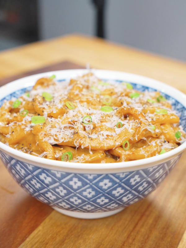Finished Creamy Miso Butter Noodles Recipe in a blue bowl topped with Parmesan, black pepper, and scallions.