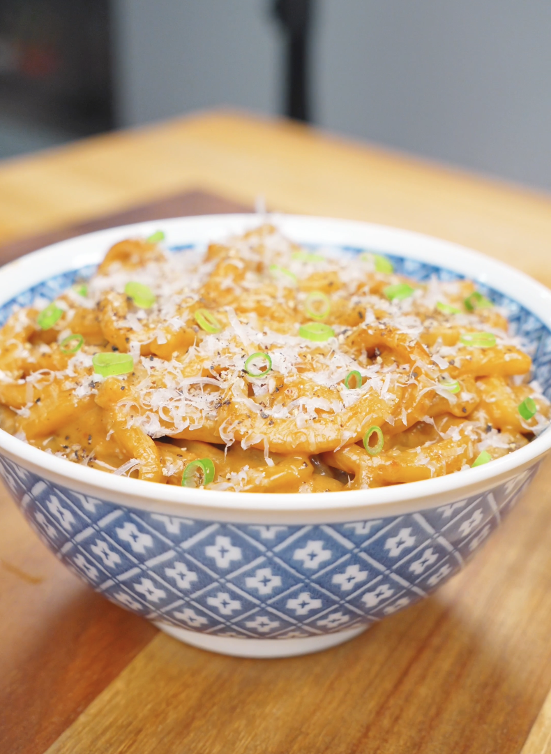 Finished Creamy Miso Butter Noodles Recipe in a blue bowl topped with Parmesan, black pepper, and scallions.