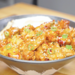 Finished Firecracker Chicken Recipe served over rice with sesame seeds, scallions, and a fried egg.