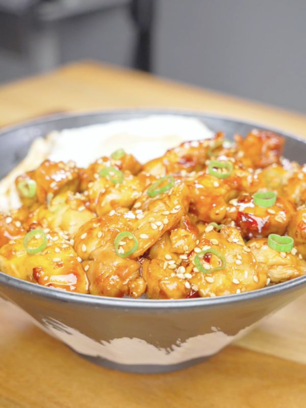 Finished Firecracker Chicken Recipe served over rice with sesame seeds, scallions, and a fried egg.
