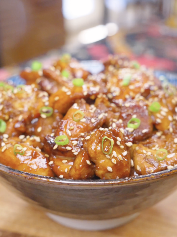 Finished Honey Sesame Chicken Recipe in a ceramic bowl topped with sesame seeds and sliced scallions.