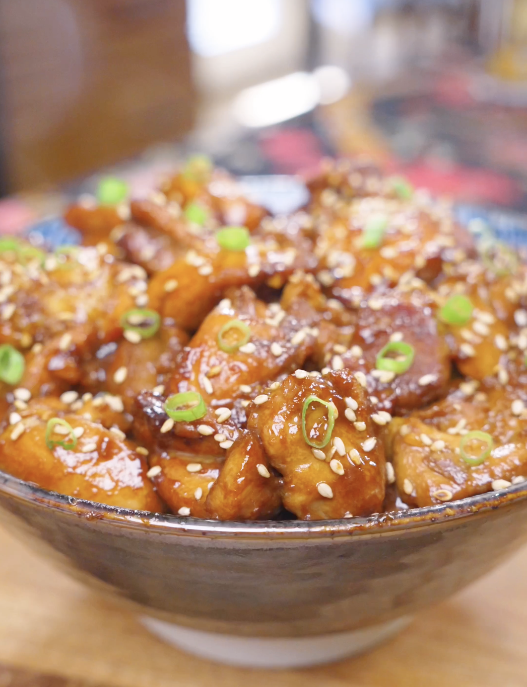 Finished Honey Sesame Chicken Recipe in a ceramic bowl topped with sesame seeds and sliced scallions.