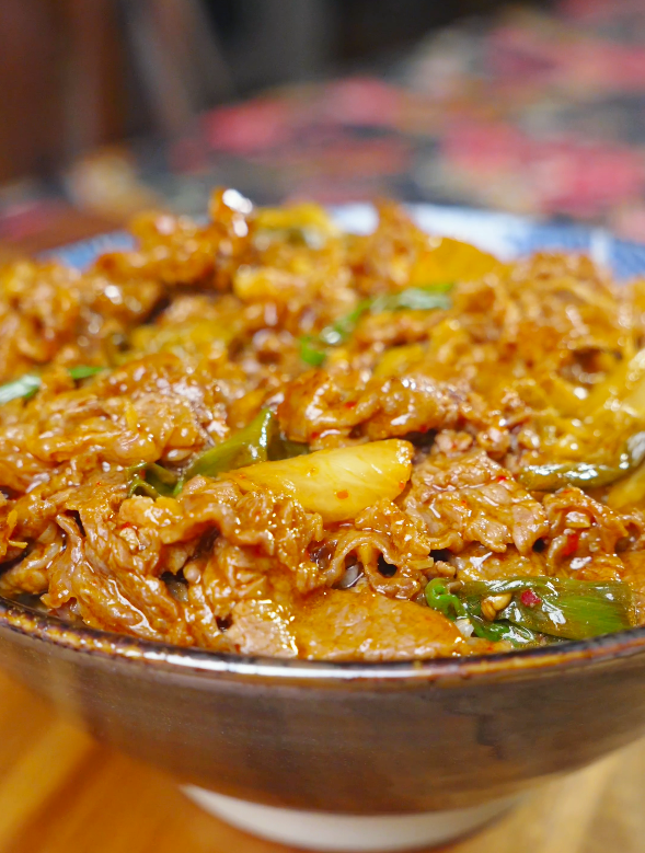 Finished Kimchi Beef Stir Fry Recipe in a ceramic bowl with beef, kimchi, and scallions.