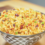 Finished Spicy Peanut Noodles Recipe in a patterned bowl topped with chili crisp and sliced scallions.