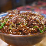 Finished Teriyaki Beef Recipe in a ceramic bowl with scallions and sesame seeds.