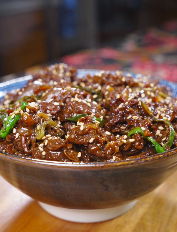 Finished Teriyaki Beef Recipe in a ceramic bowl with scallions and sesame seeds.