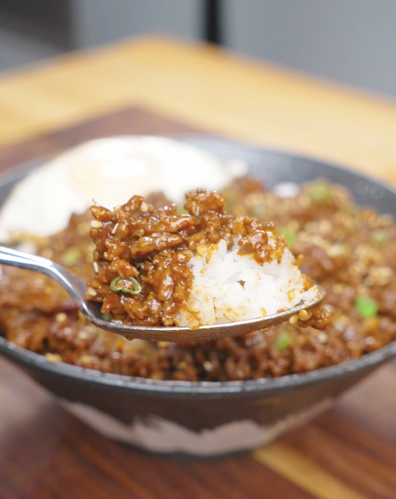 A spoonful of saucy beef and rice lifted above the bowl of Garlic Butter Ground Beef Recipe.