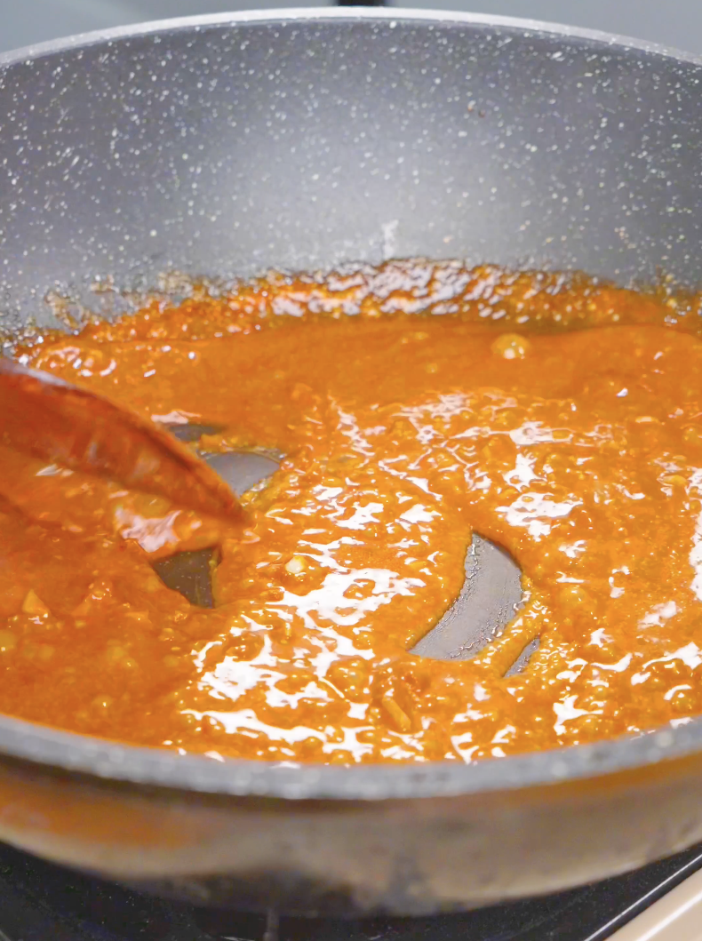 A glossy orange miso butter sauce simmering and thickening in the pan for Creamy Miso Butter Noodles Recipe.