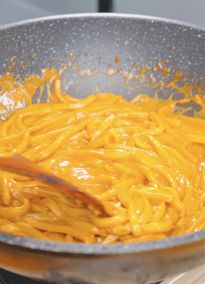 Udon noodles being tossed until fully coated in the creamy miso sauce for Creamy Miso Butter Noodles Recipe.