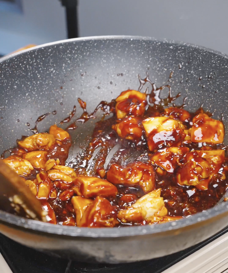 Chicken pieces being tossed in a thick, glossy soy garlic glaze for Sticky Soy Garlic Chicken Recipe.