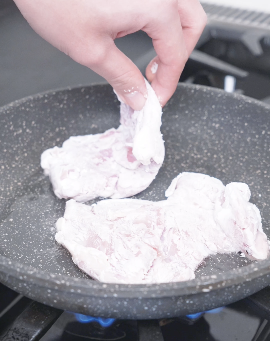 Coated chicken thighs being laid into hot oil to shallow fry for Creamy Gochujang Chicken Recipe.