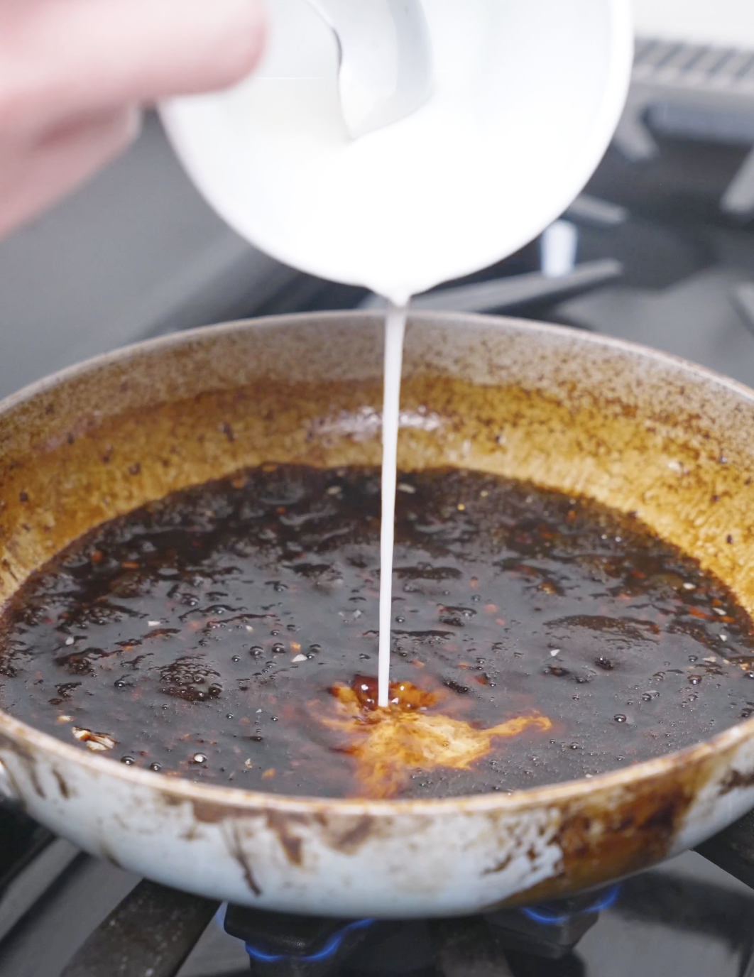 A cornstarch slurry being poured into the simmering teriyaki sauce for Teriyaki Meatballs Recipe.